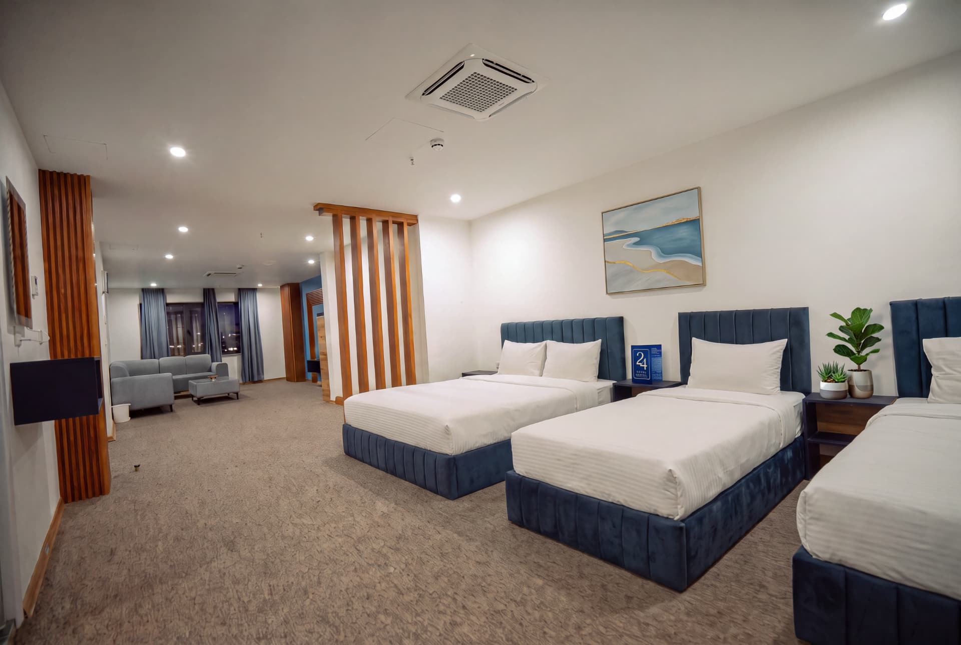 Deluxe Suite bedroom with three beds and lounge beyond